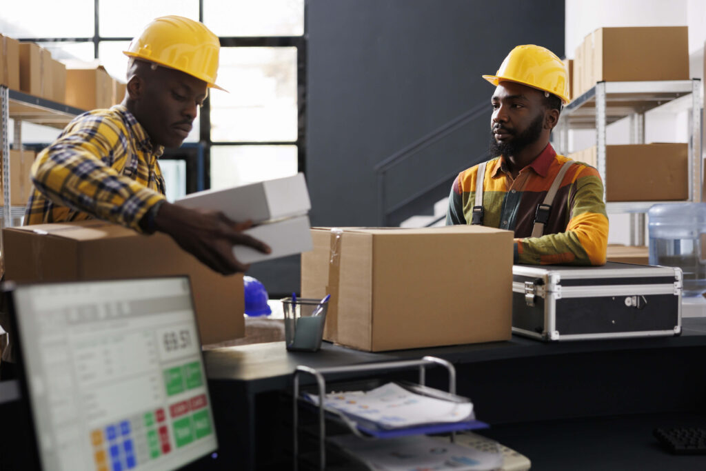 Warehouse employees putting packed boxes on counter desk ready for shipment. African american e commerce retail storehouse managers preparing customer packages for transportation